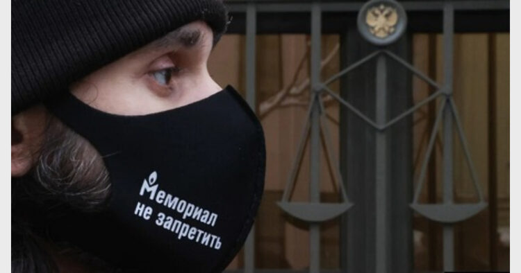 रूस के सर्वोच्च न्यायालय के गेट पर 'मेमोरियल' समर्थक द्वारा पहने इस मास्क पर लिखा है-'मेमोरियल पर किसी तरह प्रतिबंध नहीं लगाया जा सकता'। (फाइल चित्र)