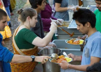 इस्कॉन से जुड़े कृष्ण भक्त लोगों को भोजन वितरित करते हुए