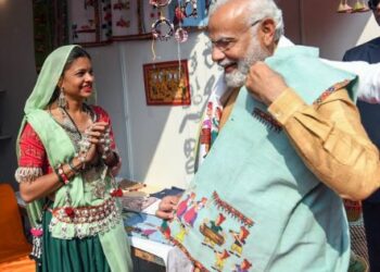 एक स्टॉल पर कलाकार से बात करते और पोषाक देखते प्रधानमंत्री श्री नरेंद्र मोदी