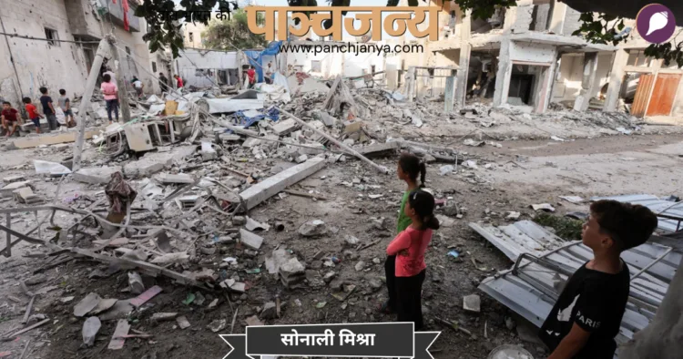 मध्य गाजा पट्टी के मघाज़ी शरणार्थी शिविर में, इज़राइल-हमास संघर्ष के बीच, फ़िलिस्तीनी बच्चे एक घर पर हुए इज़राइली हमले की जगह पर खड़े हैं। (फाइल फोटो- रॉयटर्स/एएनआई)